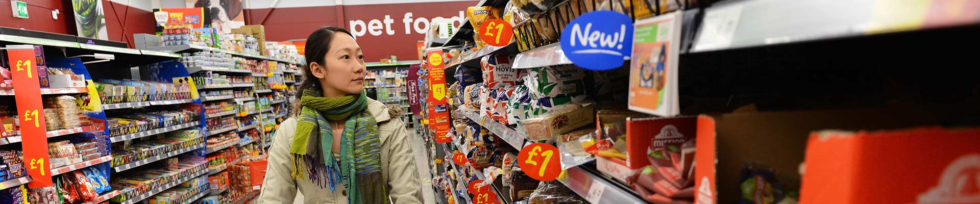 A student shopping in a supermarket with a trolley and savings signs