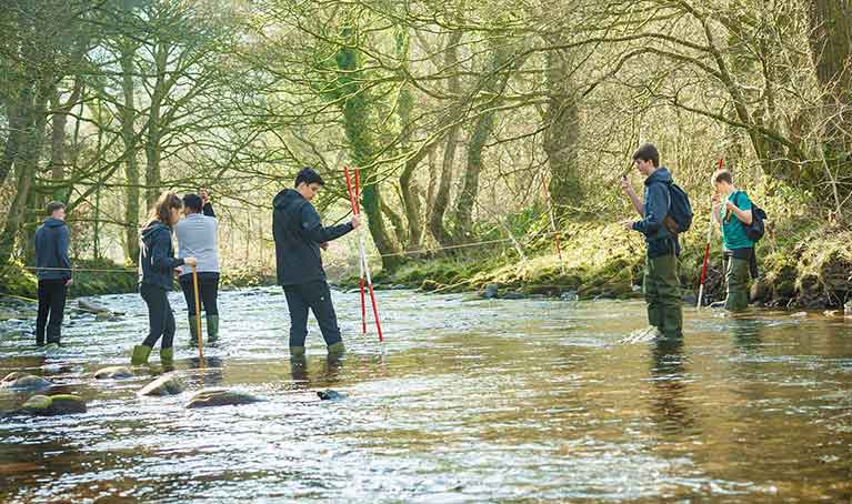 Group of students stood in shallow water measuring the flow