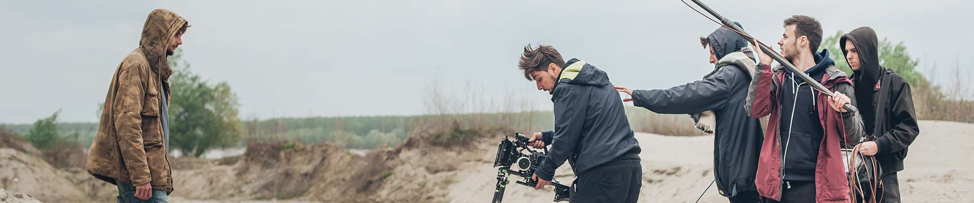 An actor and film crew filming on a sandy beach