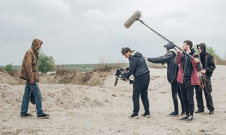 An actor with his crew on a beach