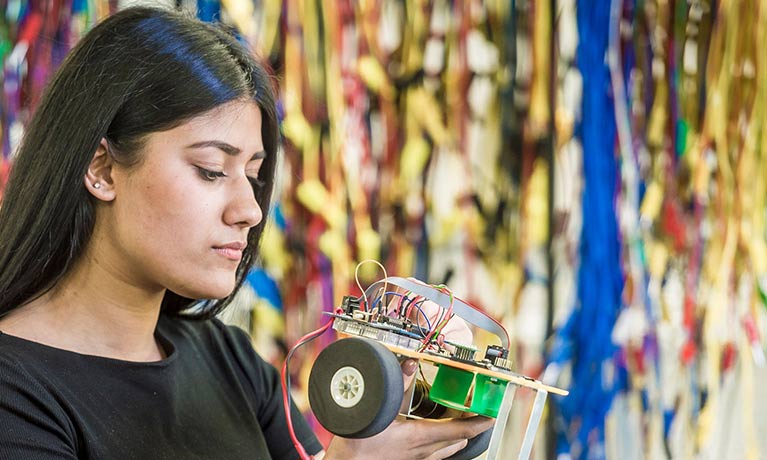 Female student working on a small model car