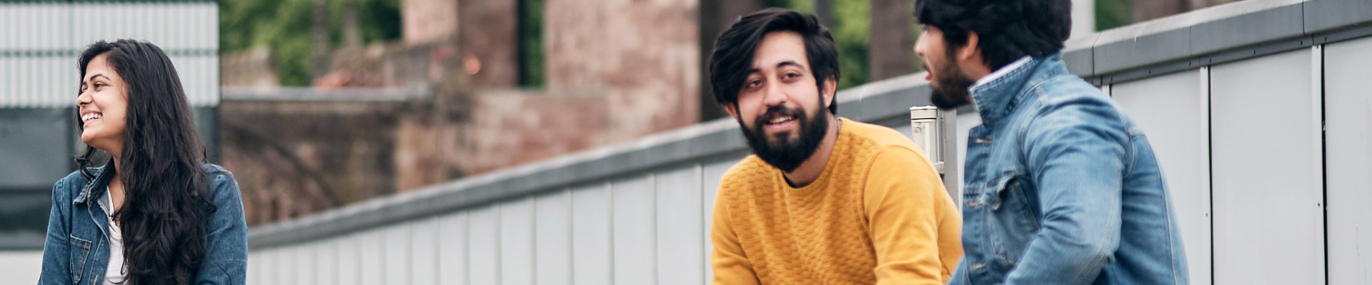 Two international students sat in the rooftop garden of The Hub with the cathedral ruins behind them.