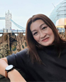 Portrait of Sherry Cheong outside with a bridge going over a river in the background.