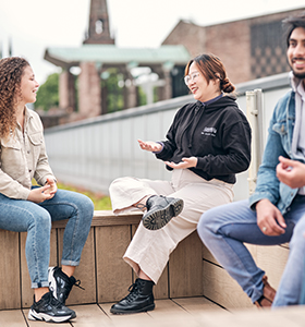 Students talking and laughing with a view of the cathedral behind them