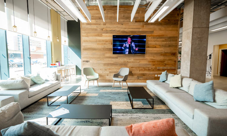 A communal area in Bishopsgate accommodation with sofas and a flat screen television on the wall.