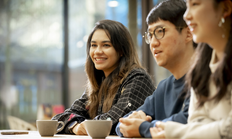 Group of students sat at a table smiling
