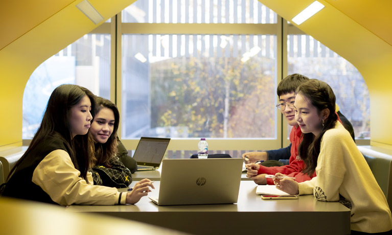 Four international students sat in a booth inside The Hub.