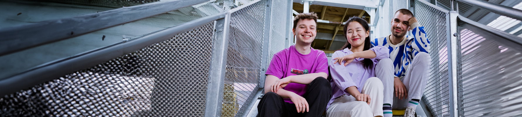 Three students sitting on an external stairwell