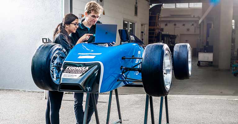 Students looking at a computer analysing a race car
