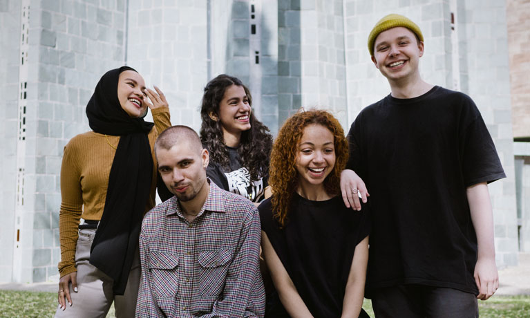 Four students standing together laughing and smiling