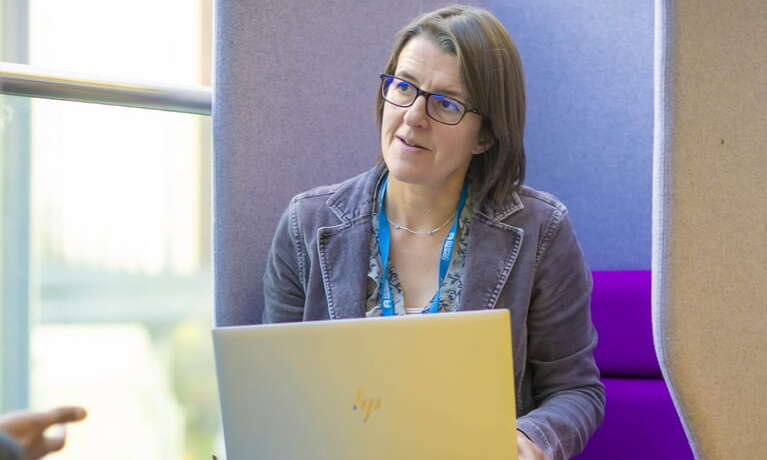 Female student advisor sitting behind a laptop smiling at the camera