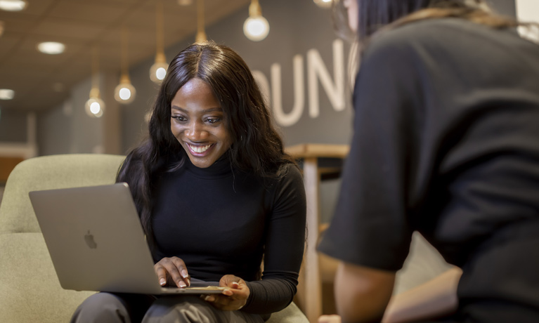 A student smiling enthusistically while looking at her laptop.