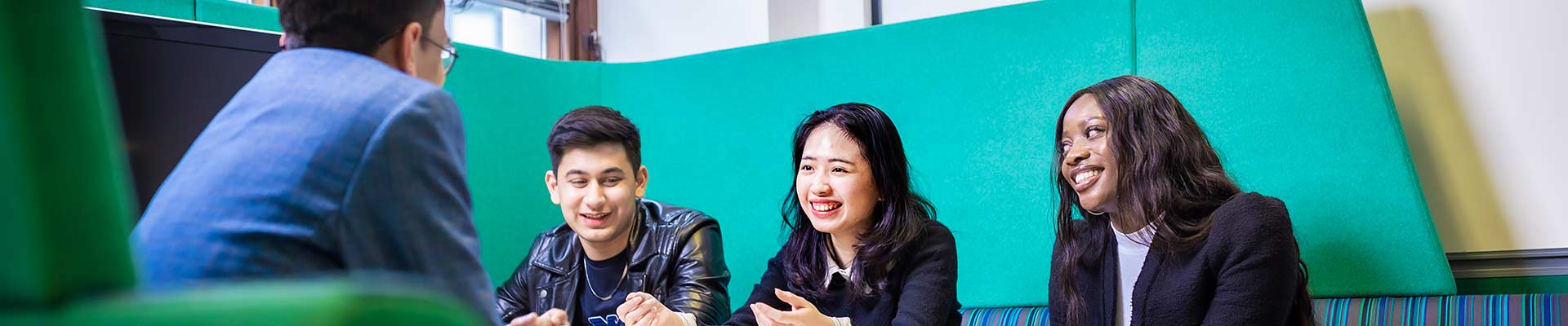 Three students sitting in a study booth facing another person