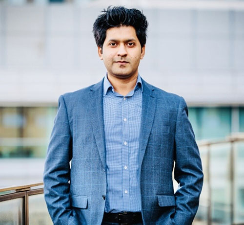 Portrait of Dr Junaid Khan wearing a shirt and blazer with an out of focus background