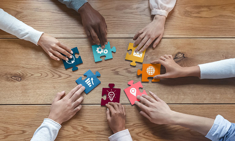 An overhead image of hands with puzzle pieces coming together