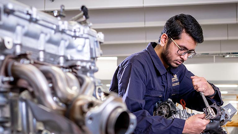 Male student working on a piece of mechanical part