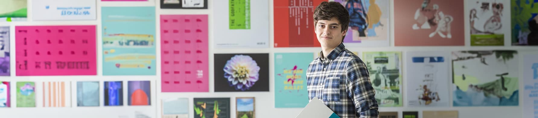 Student stood against a wall with art work