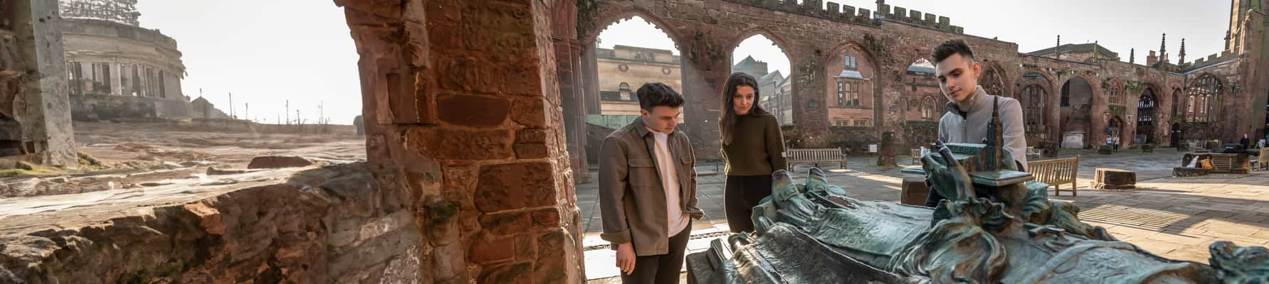 Students looking at a sculpture in the Coventry Cathedral ruins