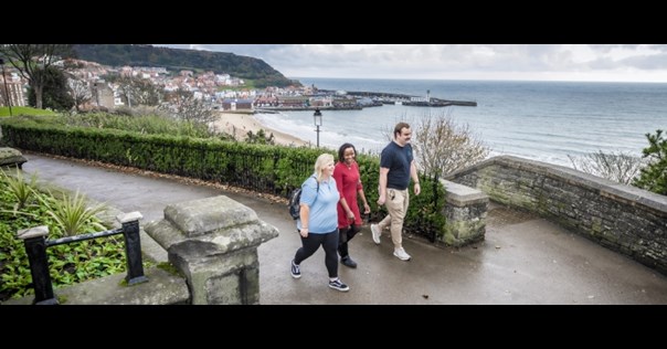 Three people walking with the Scarborough beach in view