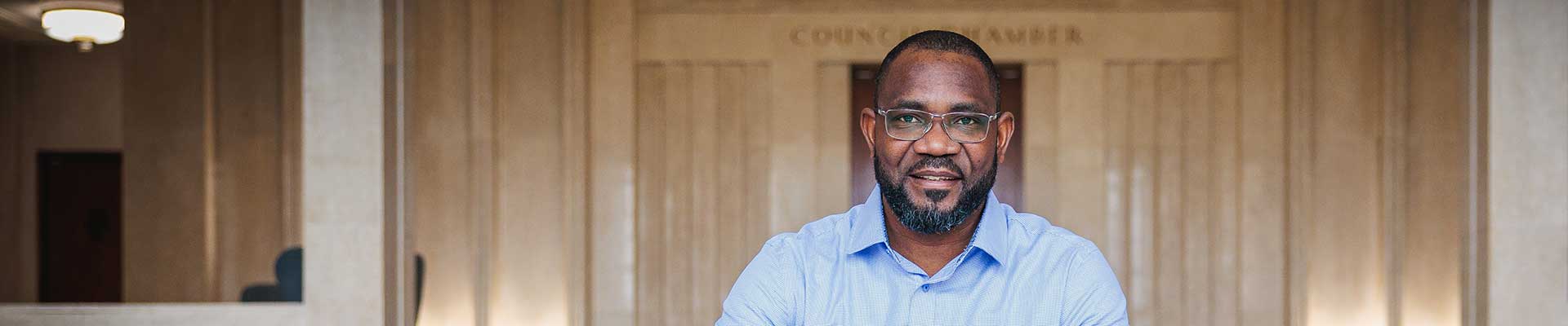 Male student sat on a couple of steps inside a building