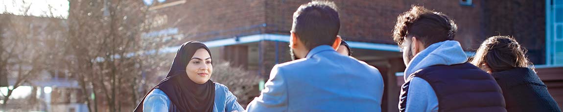 Four students sat outside in the sun talking