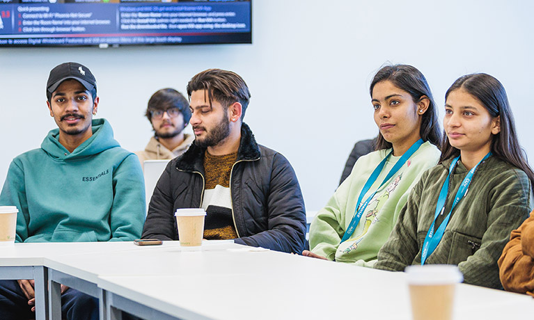 Group of students sat at a table looking ahead