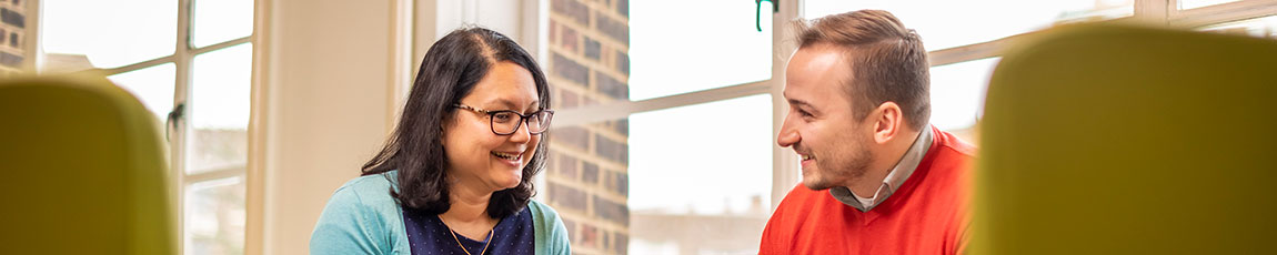 Two students stood in a classroom smiling