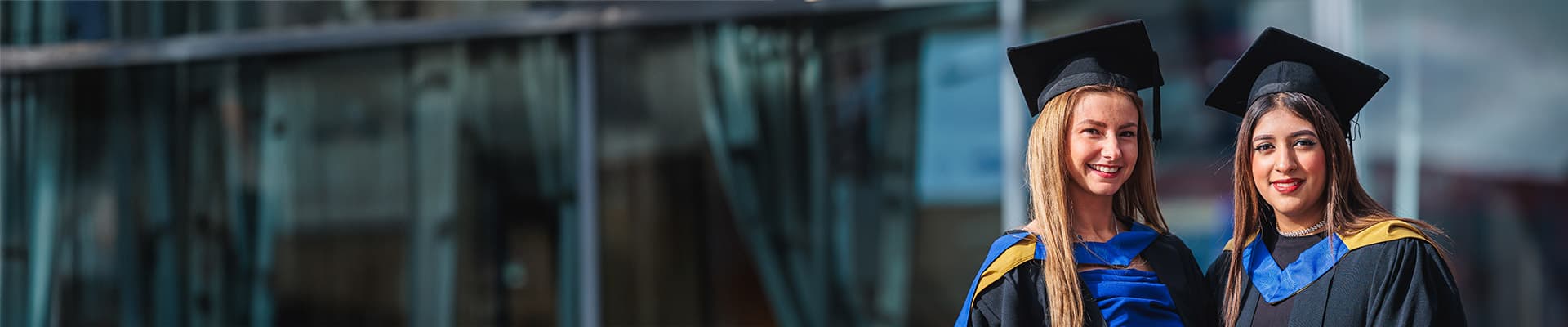 Two female graduates stood outside of a building