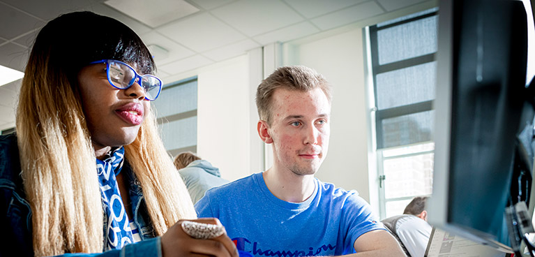 Two students working on desktops in an IT suite.