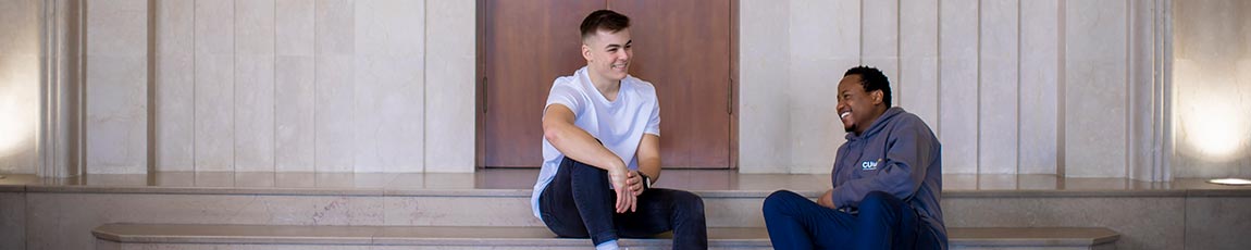 Two students sat on steps talking and laughing