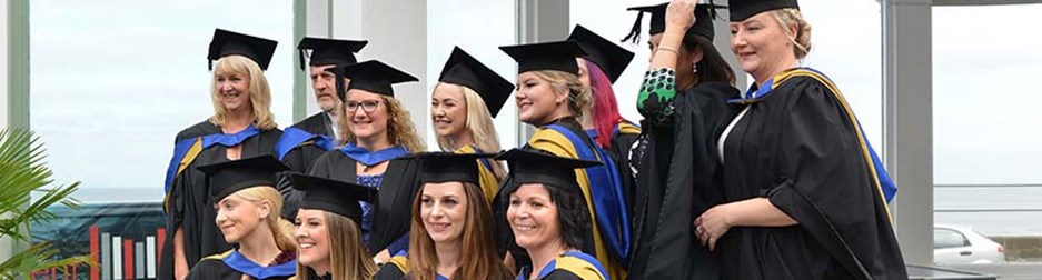 Group of students in their graduation caps and gowns smiling and laughing