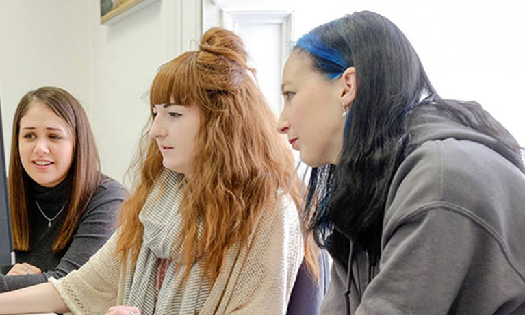 Three female students looking towards a screen