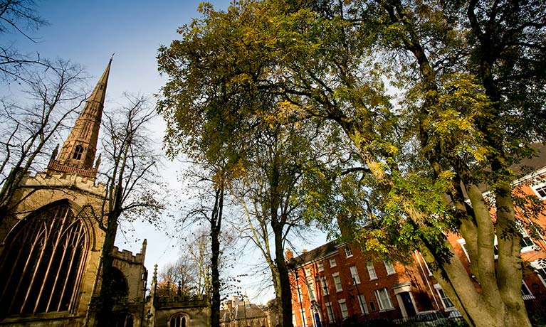 Coventry Cathedral spire surrounded by green trees