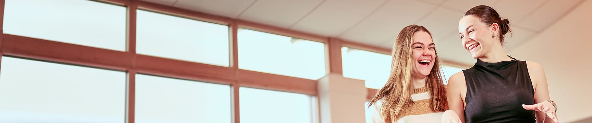 Two students smiling and laughing in an open plan area