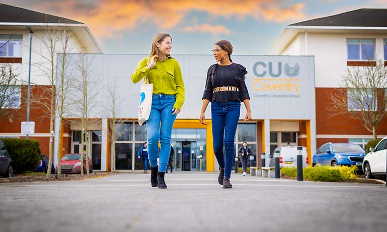 Two students walking away from the CU Coventry building