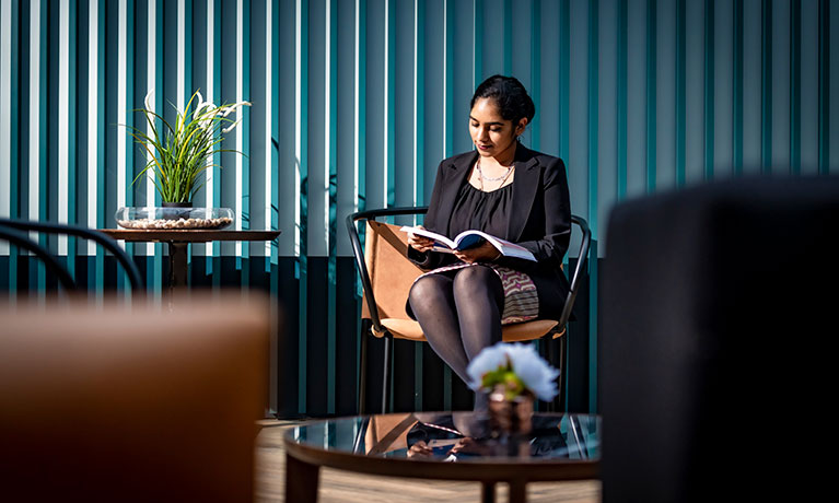 Lady reading on a chair on a blue background