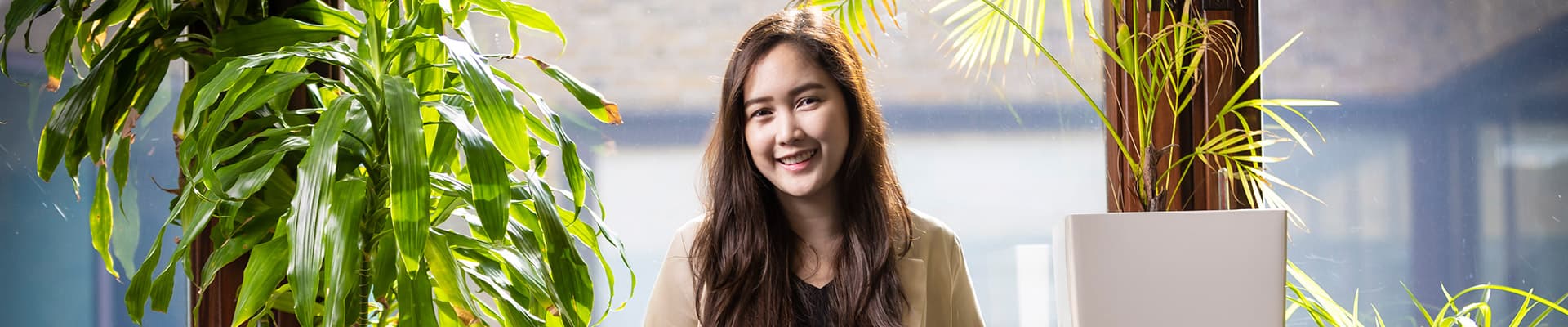 Female student leaning against a table with green plants