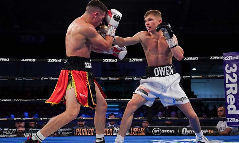 Macauley Owen wearing white shorts in action in the boxing ring against an opponent in red shorts