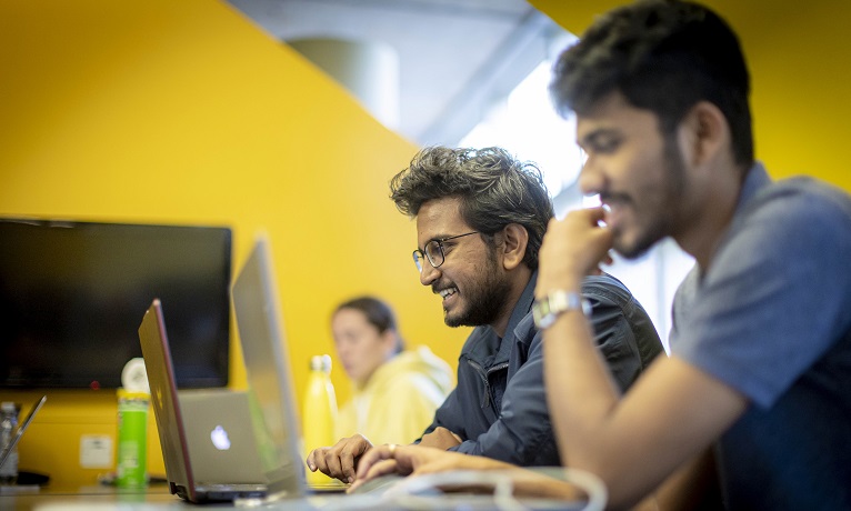 Smiling students sat working at computers at Coventry University