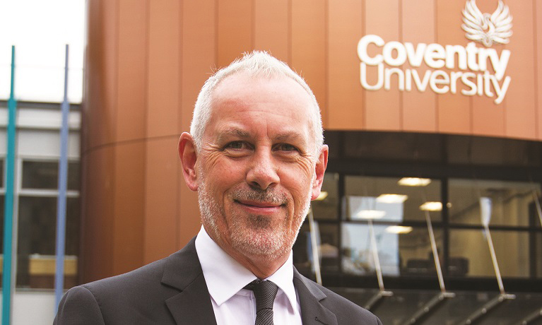 Head and shoulders image of Professor John Dishman stood infront of a building with the Coventry University logo on it