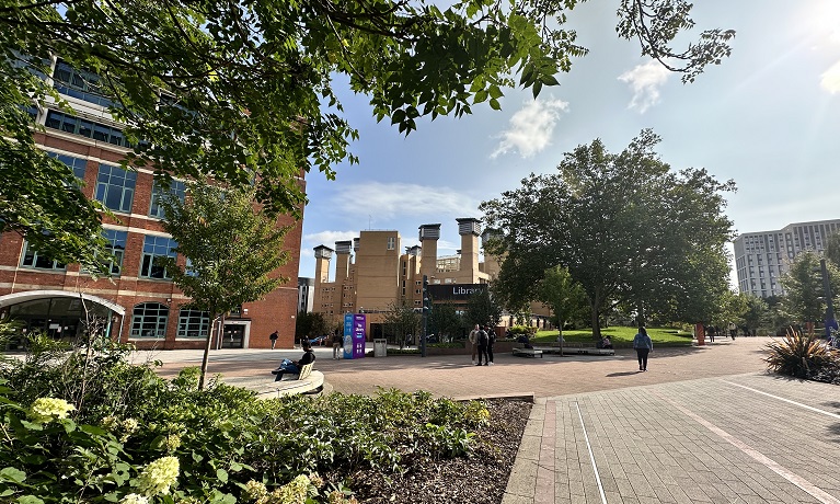 The William Morris Building and Coventry University Library next to each other with green trees and blues skies