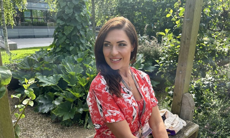 Coventry University psychologist Rachael Molitor wearing a red flowery dress looking off to the side of the camera