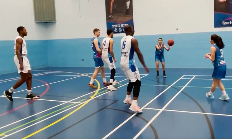 A group of males and females playing basketball