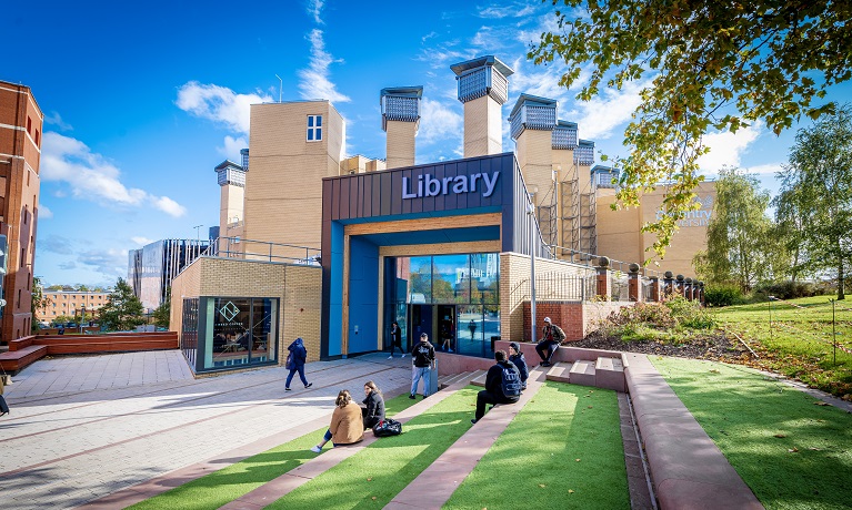 People sat on green steps outside Coventry University Library