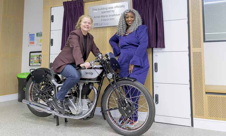 Beatrice Shilling’s great-niece Jo Denbury sits on a classic Norton motorcycle and is joined by Dr Anne-Marie Imafidon MBE for the opening of Coventry University's new Beatrice Shilling building