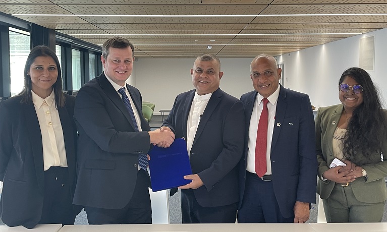 Representatives of Coventry University and NIBM stood in a line with two of them holding a copy of the agreement