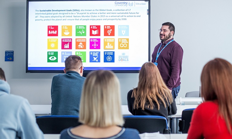 A staff member at Coventry University Wrocław stood by an interactive whiteboard speaking to students