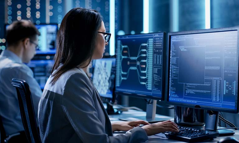 woman sits on a computer in a dark room