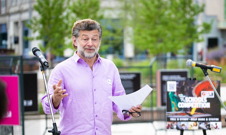 Andy Serkis standing outside holding a piece of paper