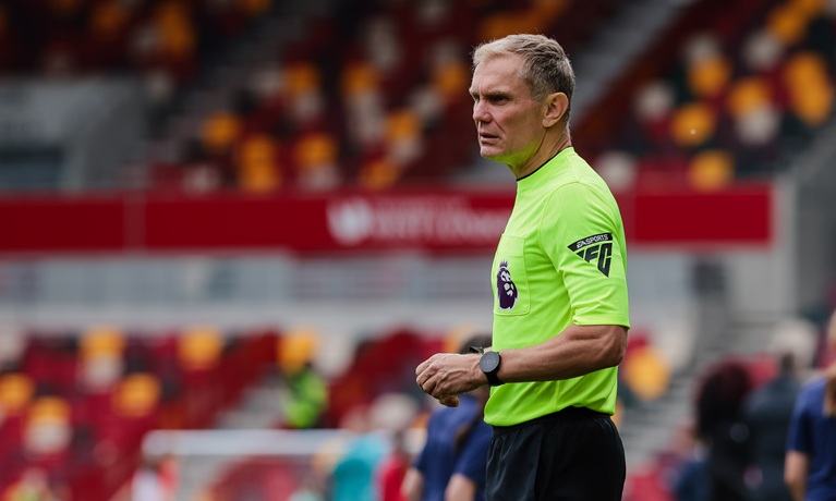 Graham Scott in his referee kit inside a football stadium looking off to the left of the camera